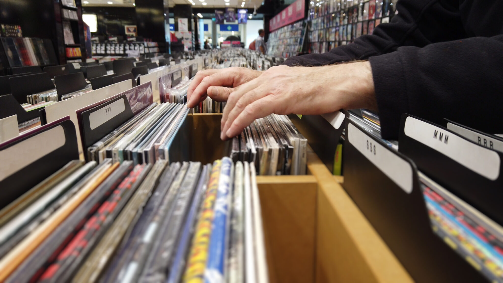Close up of hands flipping through lps in a large record shop.