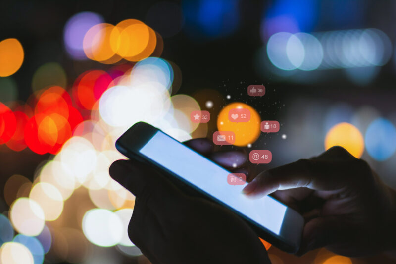 Soft focus man using his mobile phone or smartphone with icons on night street bokeh background ,Businessman using ,Social, media, Marketing concept.