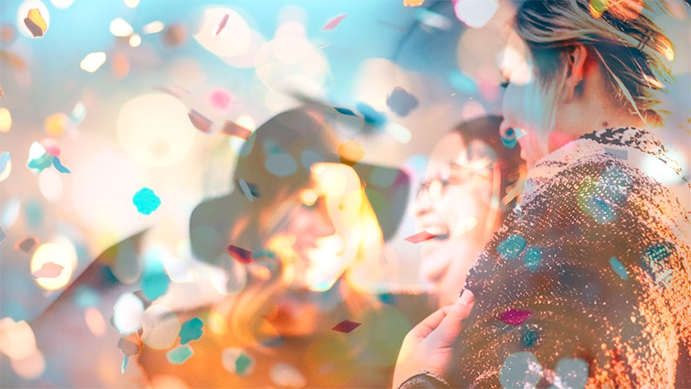 Iloisia ihmisiä nauramassa confettisateessa.