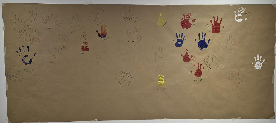 : Ruskealla paperilla eri värisiä kämmenen kuvia.