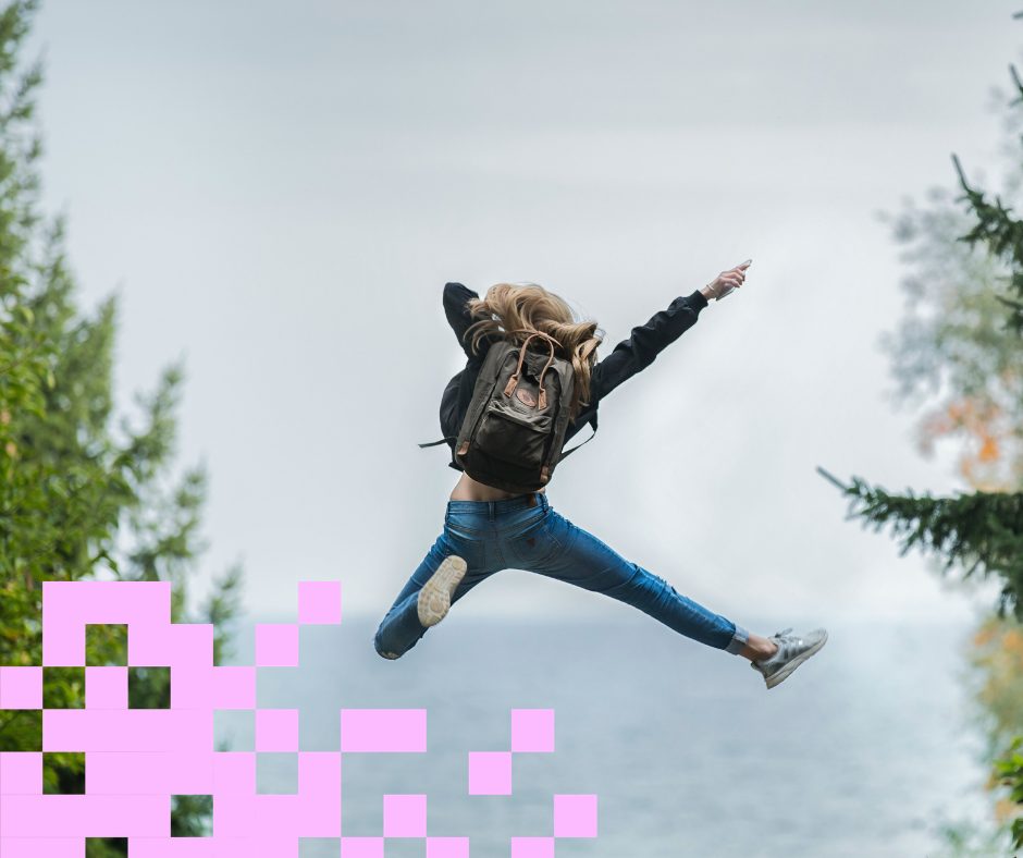 Tyttö hyppää korkealle, taustalla taivas.