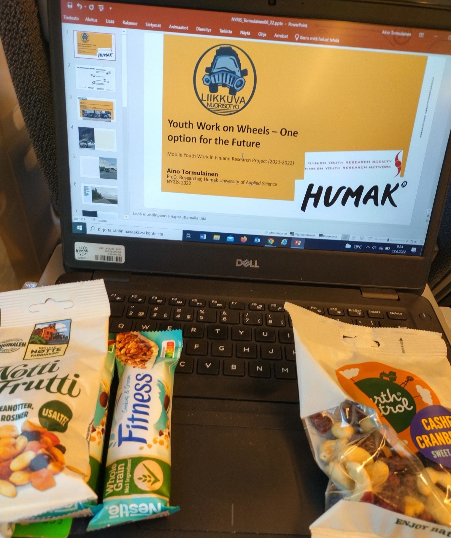 Kannettava tietokone auki, jossa esitys ”Youth Work on Wheels – one option for the future”, pähkinäpussi ja myslipatukka näppäimistöllä.