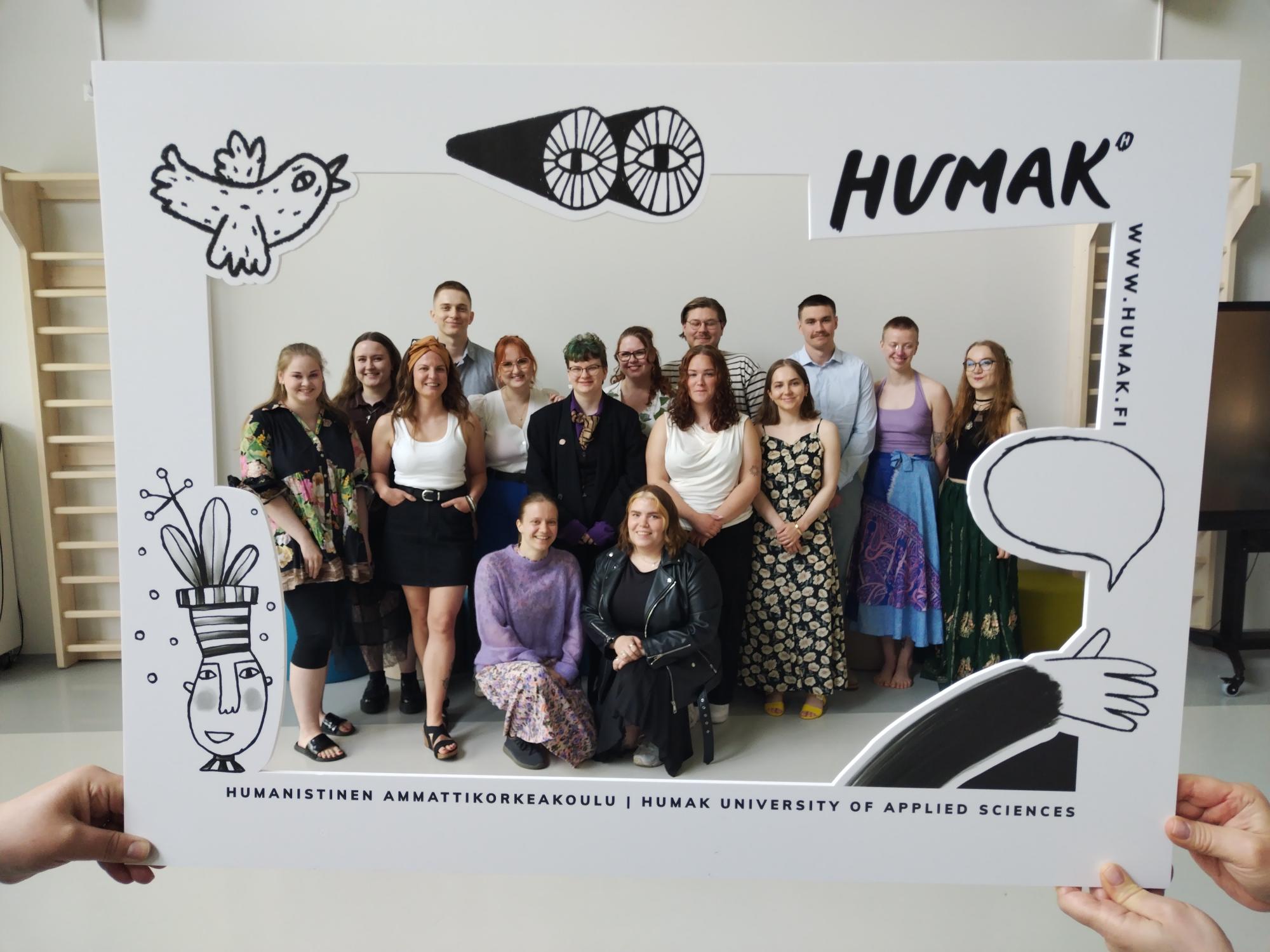 Opiskelijat hymyilevät ryhmäkuvassa, mikä on Humakin kehyksissä.