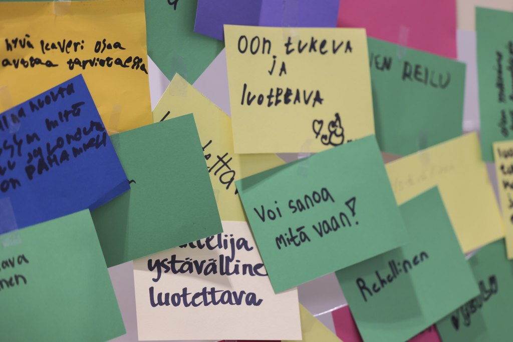 Erivärisiä muistilappuja seinällä, joihin on kirjoitettu ajatuksia siitä, millainen on hyvä kaveri.