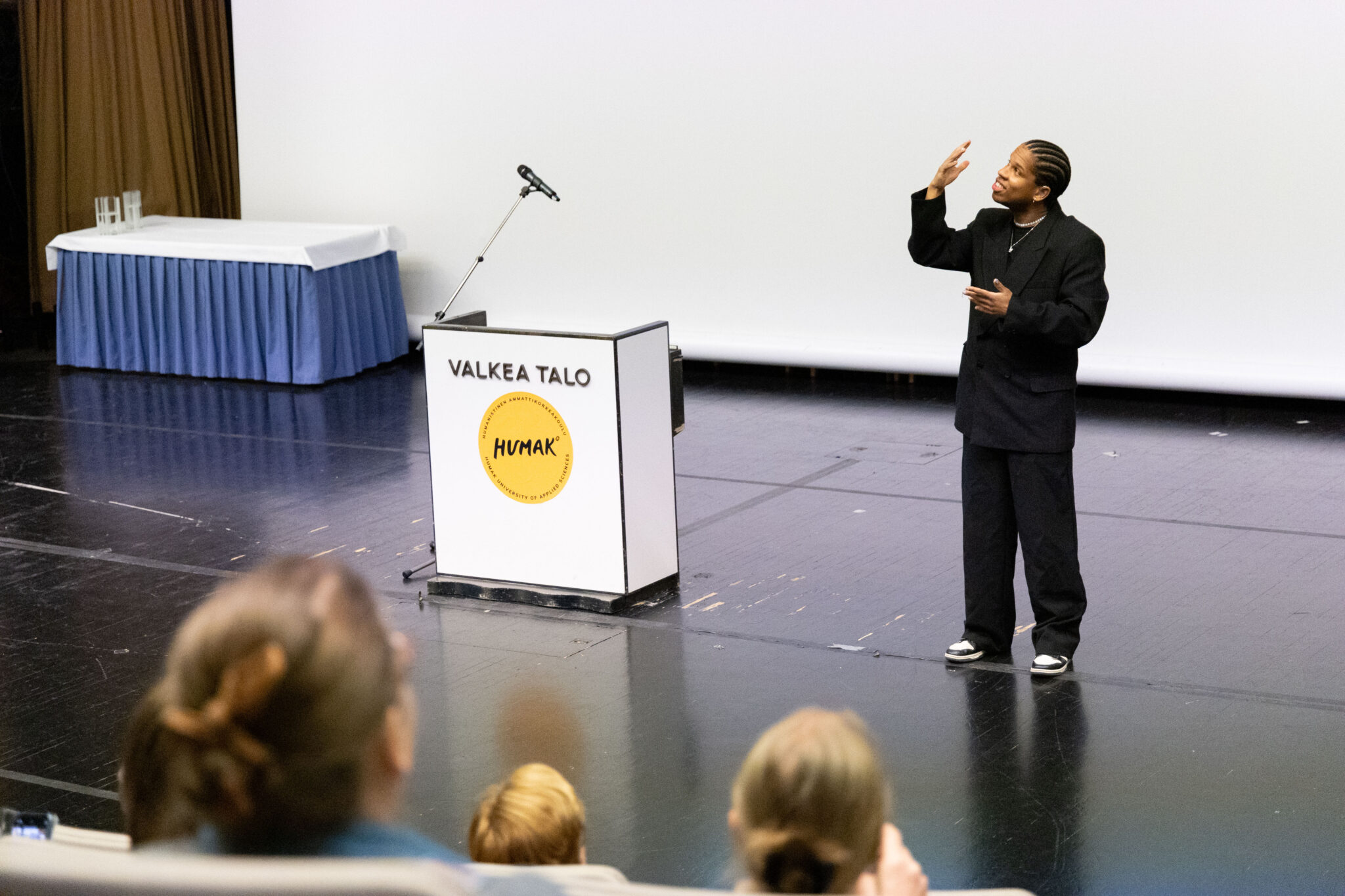 Artisti Miguel Peltomaa tulkitsee kappaletta tummiin pukeutuneena. Yleisö seuraa keskittyneenä.