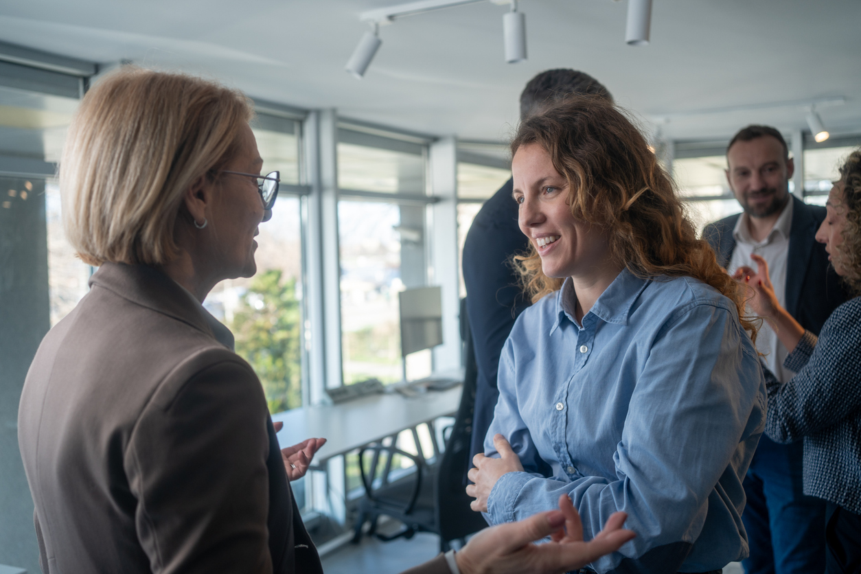 Two businesswomen having a professional conversation in modern office environment.