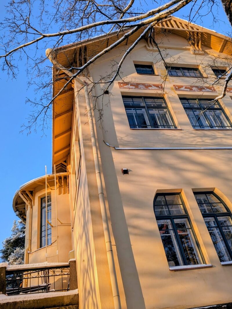 Vanhan keltaisen kivitalon päätykulmaus alhaalta ylöspäin. Takana sininen taivas.