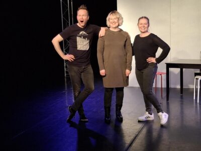 Teatterikoneen näyttelijät poseeraavat näyttämöllä seisten vieretysten.