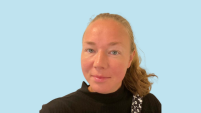 Henkilö, jolla on vaaleat hiukset ponnarilla, siniset silmät ja musta paita.