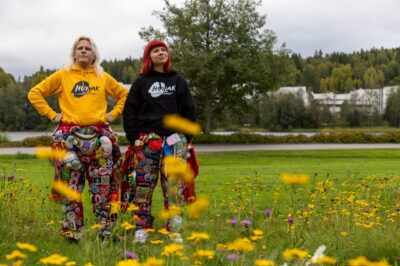 Kaksi Humakin opiskelijaa kukkapellolla punaisissa opiskelijahaalareissa, joissa on paljon haalarimerkkejä.