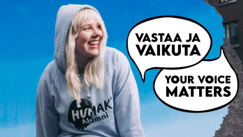 Nuori hymyilevä nainen vaaleansinisessä Humak Alumni -hupparissa katsoo vasemmalle sinistä taustaa vasten; kaksi puhekuplaa sanoilla "VASTAA JA VAIKUTA" ja "YOUR VOICE MATTERS".
